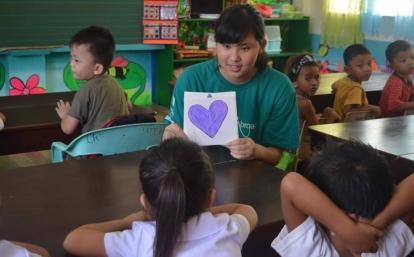 A female Japanese volunteer teaches on the Childcare project while volunteering abroad in the Philippines A Japanese Childcare volunteer teaches students about shapes on the Childcare project in the Philippines